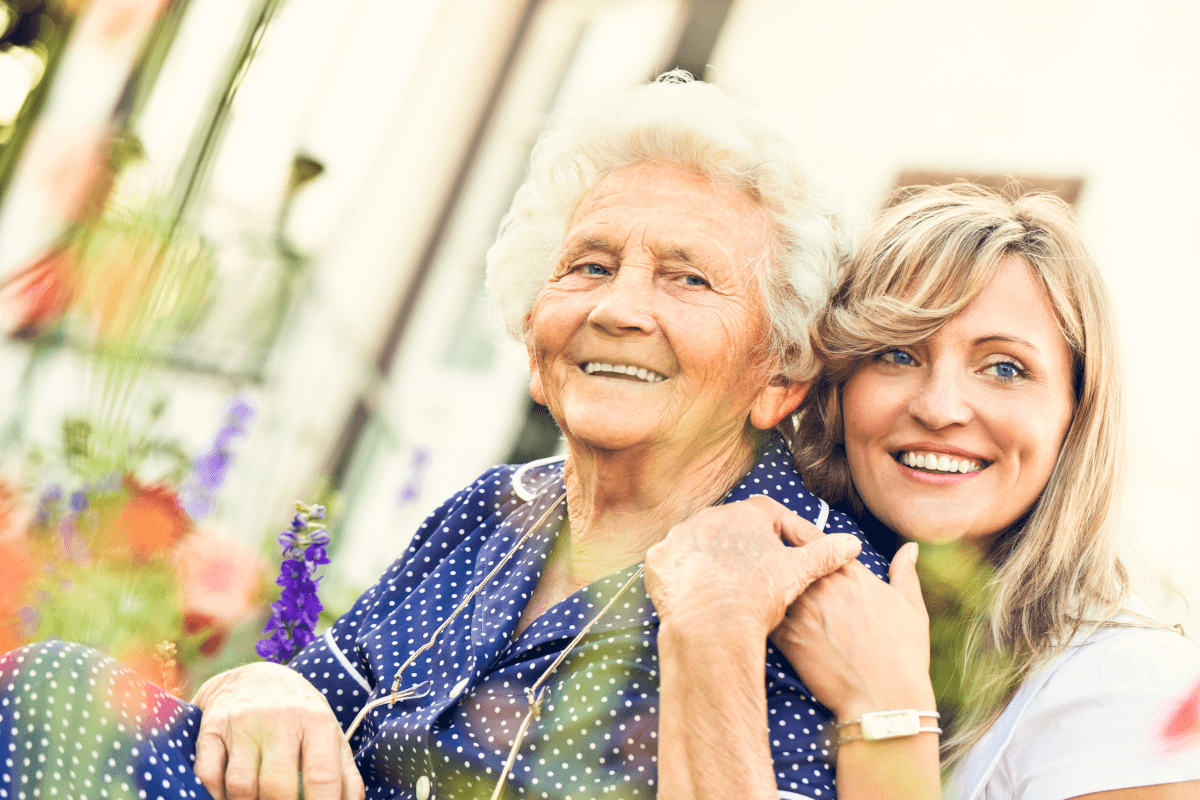 Betreuerin umarmt Seniorin liebevoll